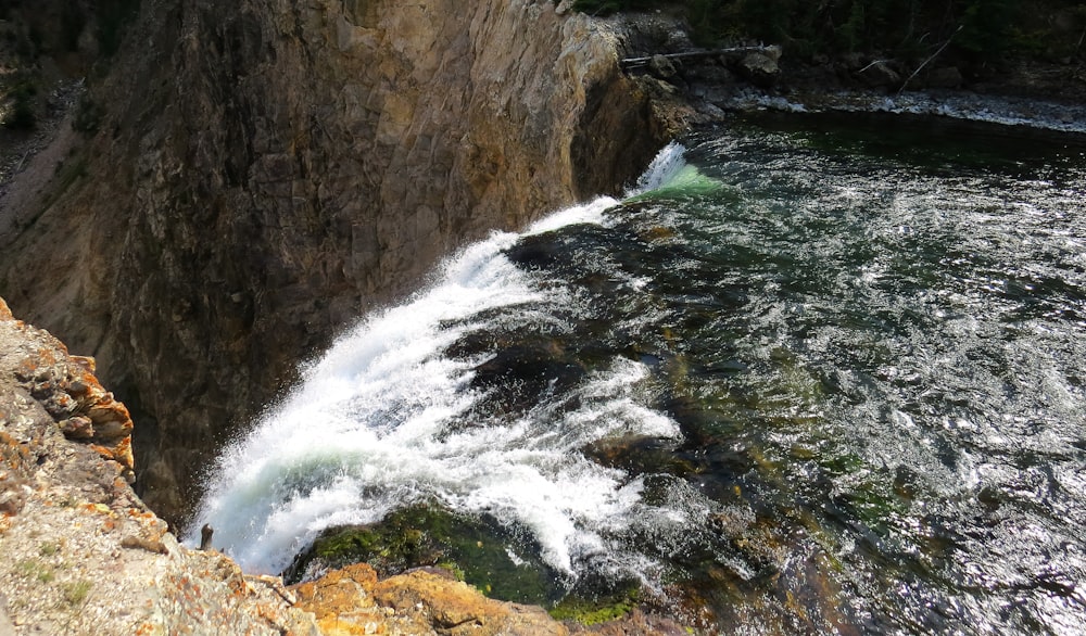 water falls on brown rocky mountain during daytime