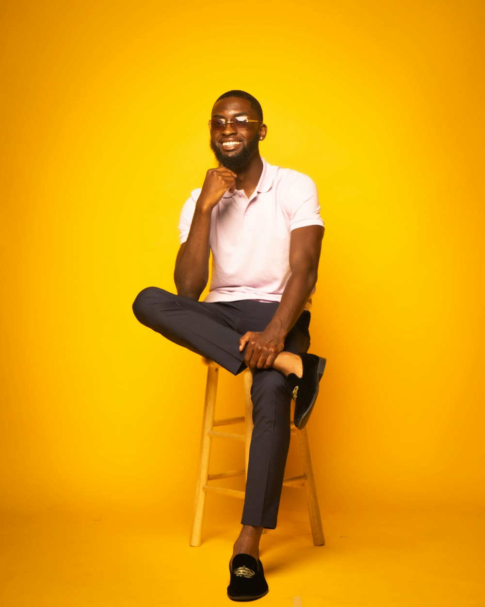 man in white polo shirt and black pants sitting on brown wooden seat