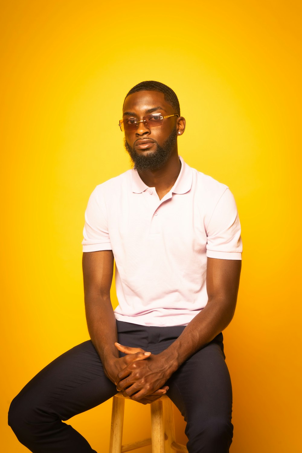 man in white polo shirt and black pants sitting on yellow chair