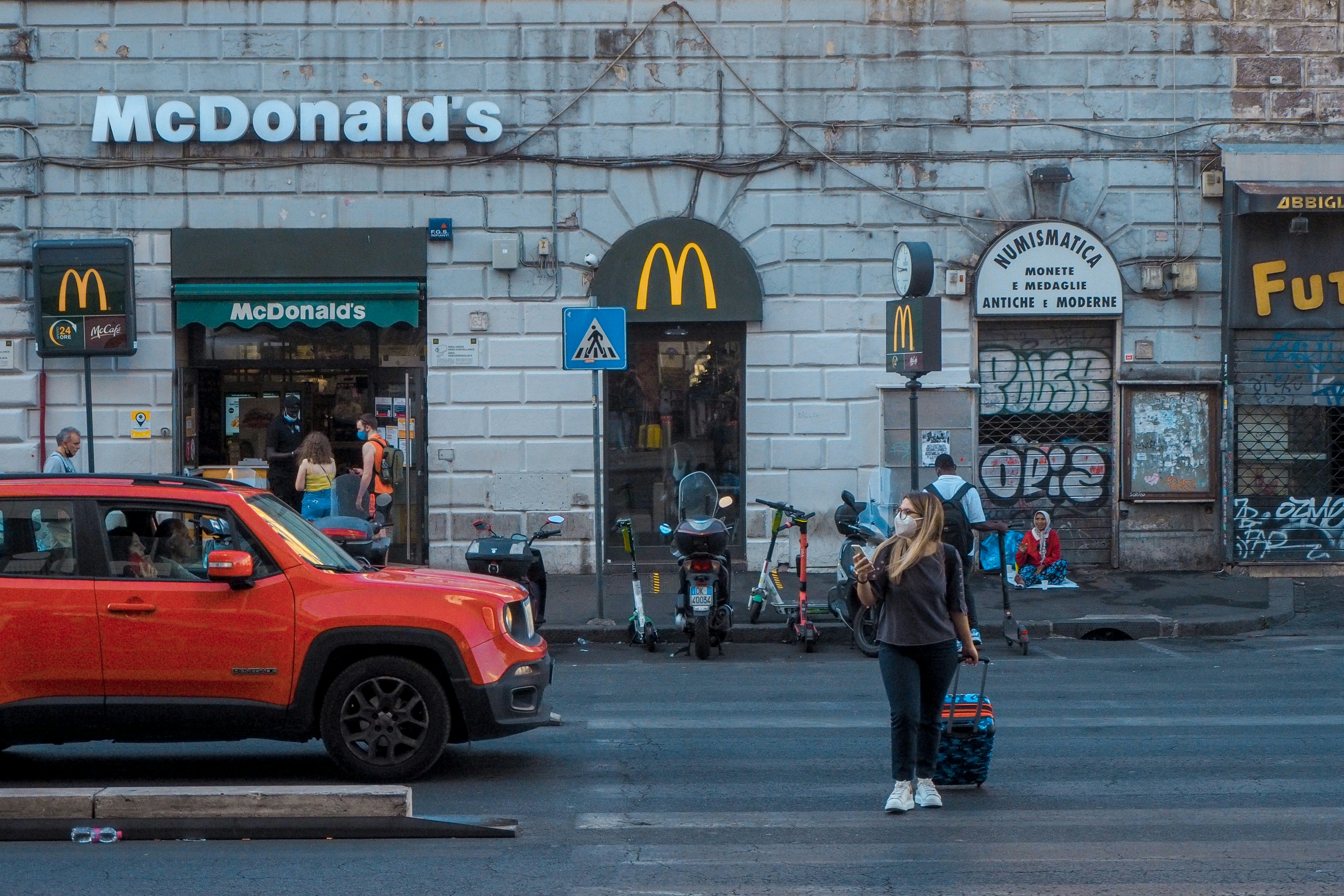 people walking on sidewalk near red car during daytime