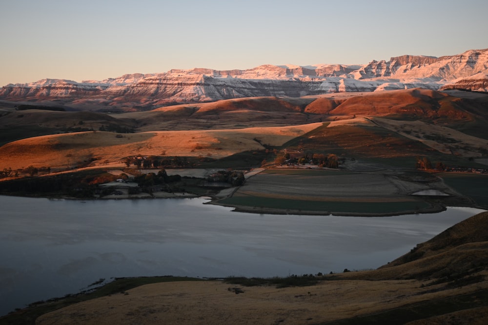 brown and white mountains beside lake during daytime