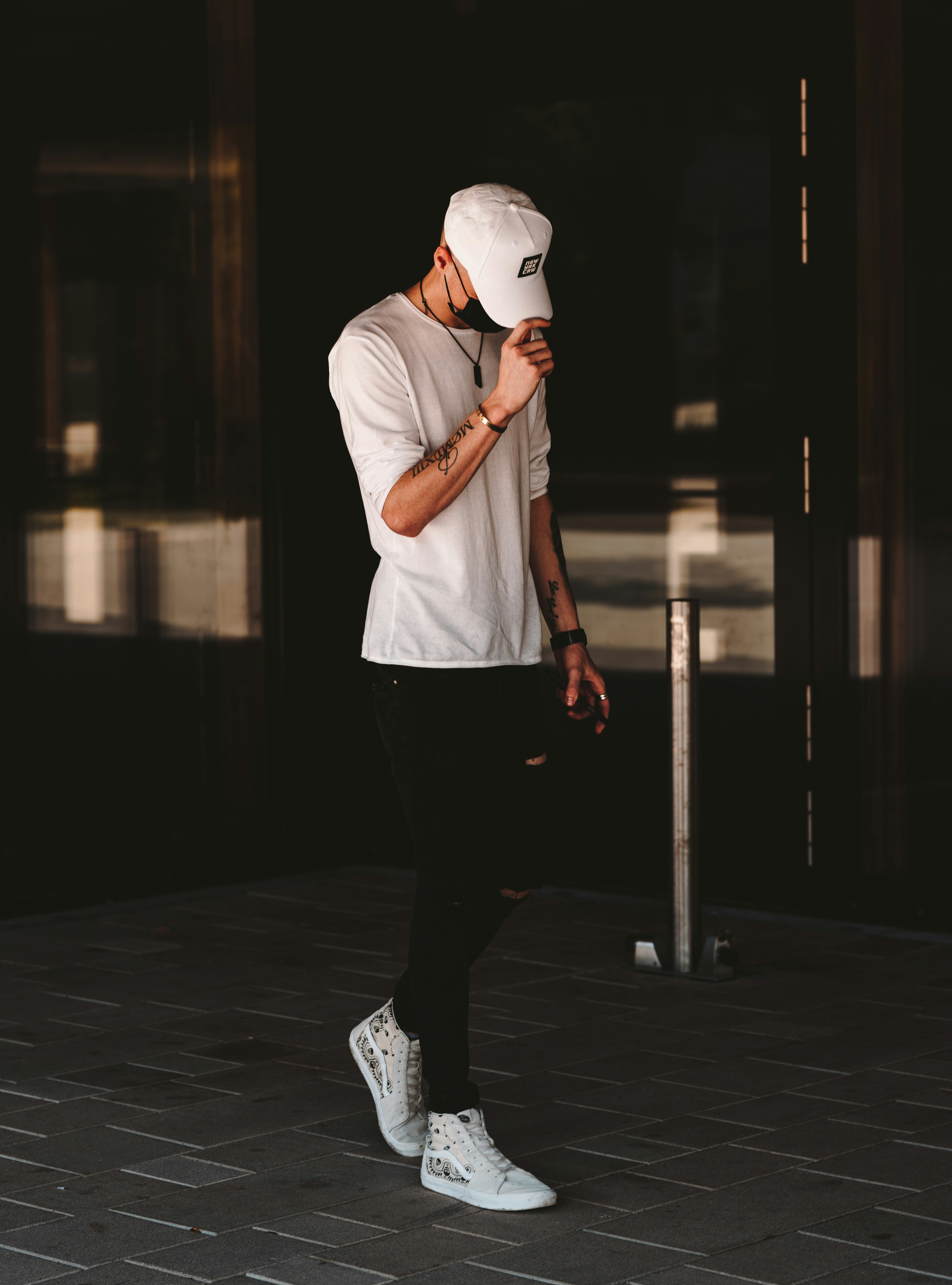 man in white t-shirt and black pants wearing white cap