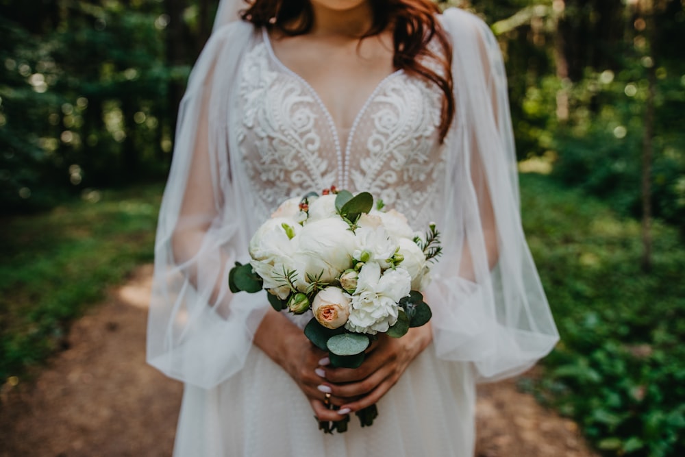 Frau in weißem Blumenkleid mit Blumenstrauß