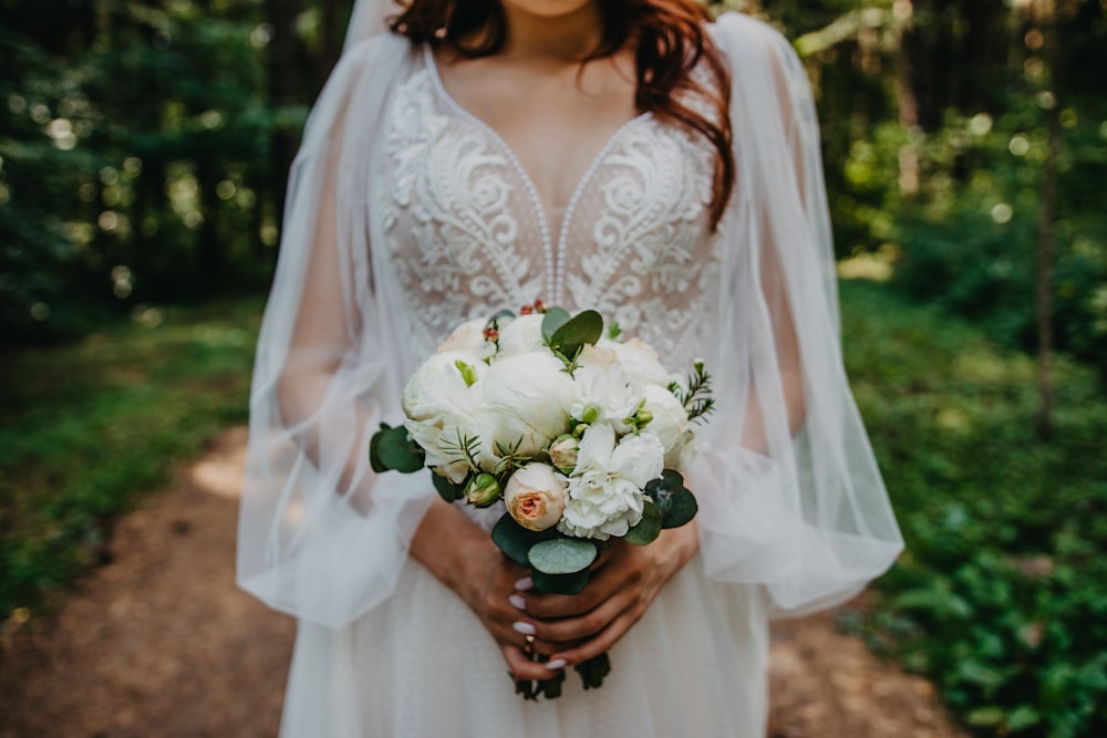 mujer en vestido floral blanco sosteniendo ramo de flores