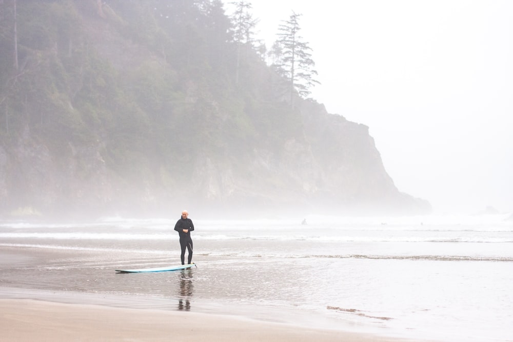 man in black jacket and black pants walking on seashore during daytime