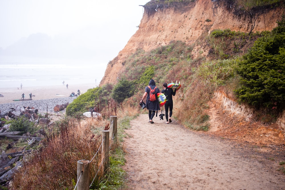 2 people walking on pathway near brown mountain during daytime