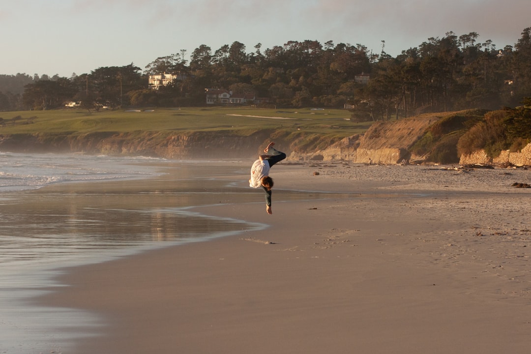 woman in white jacket and black pants running on brown sand during daytime