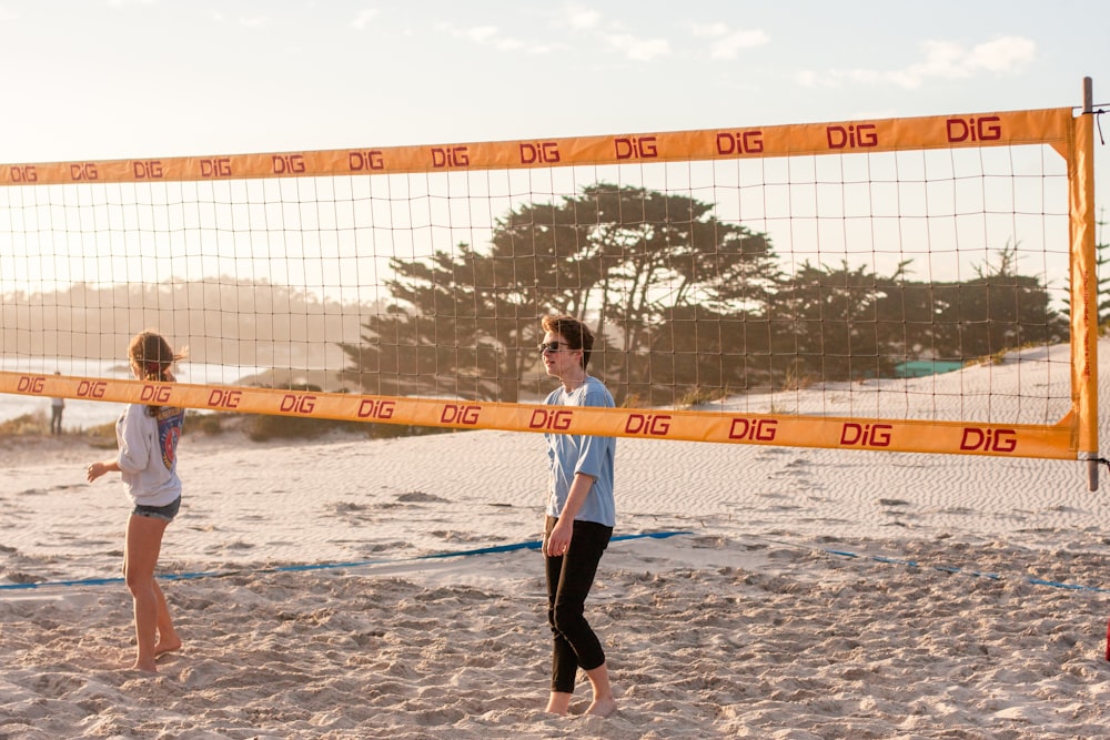 woman in white and blue jersey shirt and black pants standing on beach during daytime