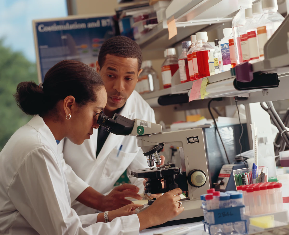 Two laboratory researchers examining a sample through a microscope