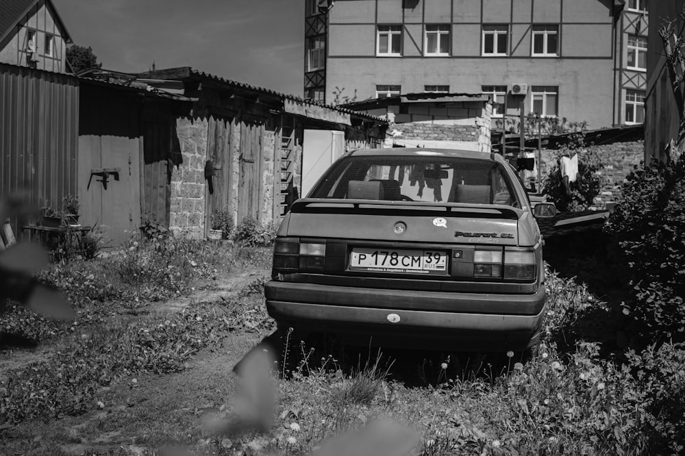 Foto en escala de grises de un coche en un campo de hierba