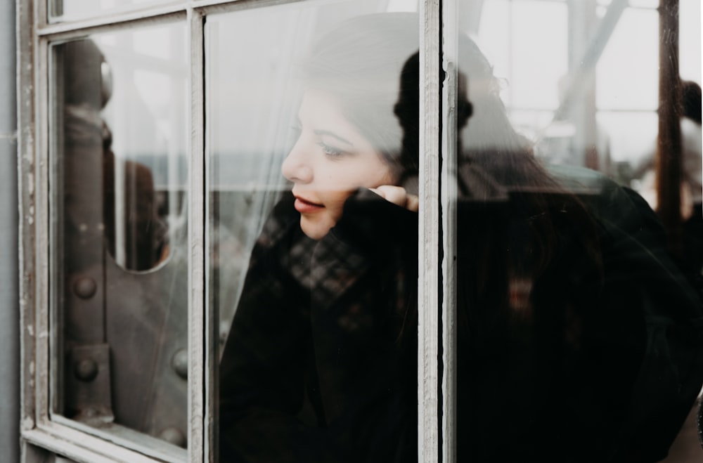 woman in black long sleeve shirt standing beside glass window