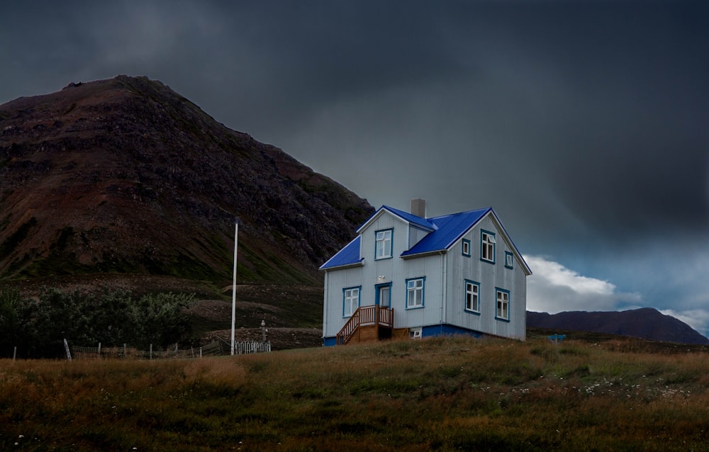 white and blue house near mountain under gray sky