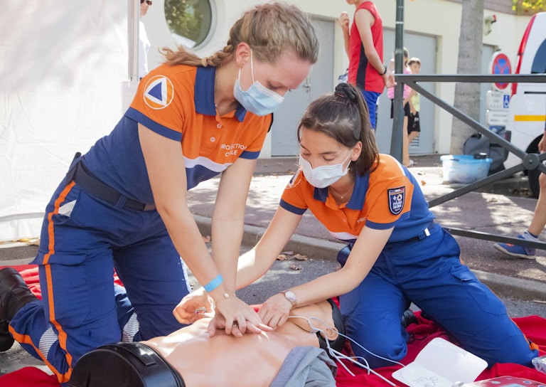 A group of young volunteers practicing first aid techniques outdoors during a training session.