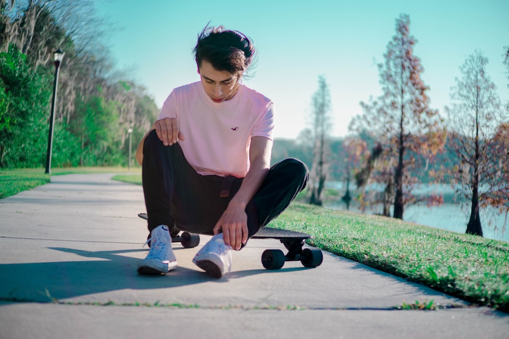 man in white crew neck t-shirt and black pants sitting on gray concrete floor during