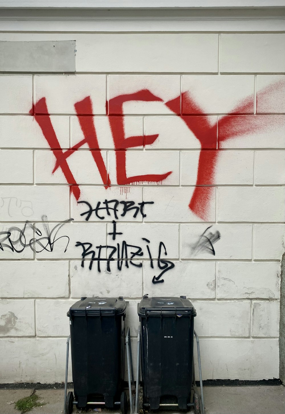 black trash bin beside white wall