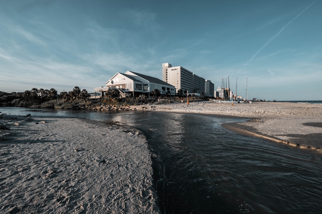 white and gray concrete building near body of water under blue sky during daytime