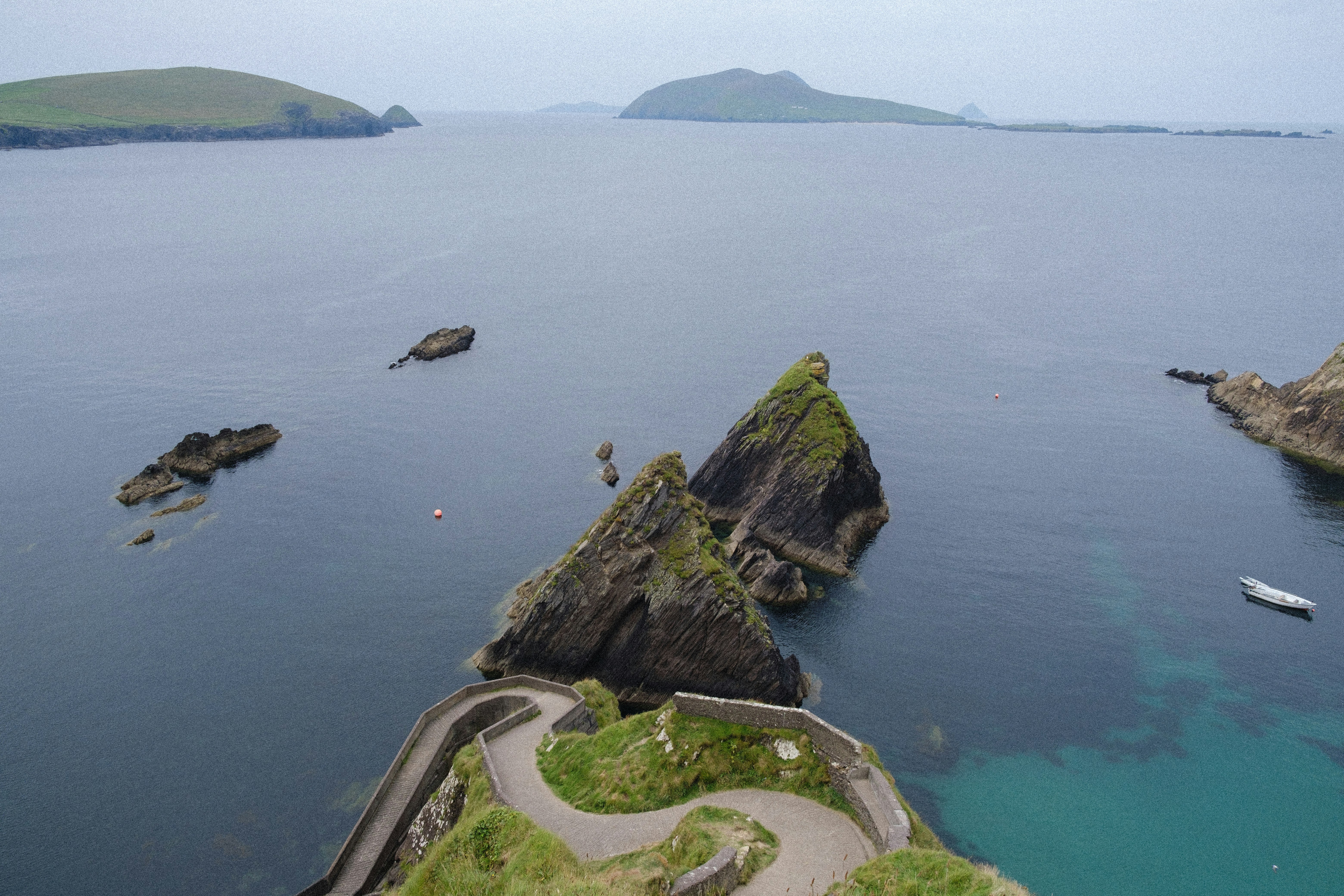 green and brown rock formation on body of water during daytime