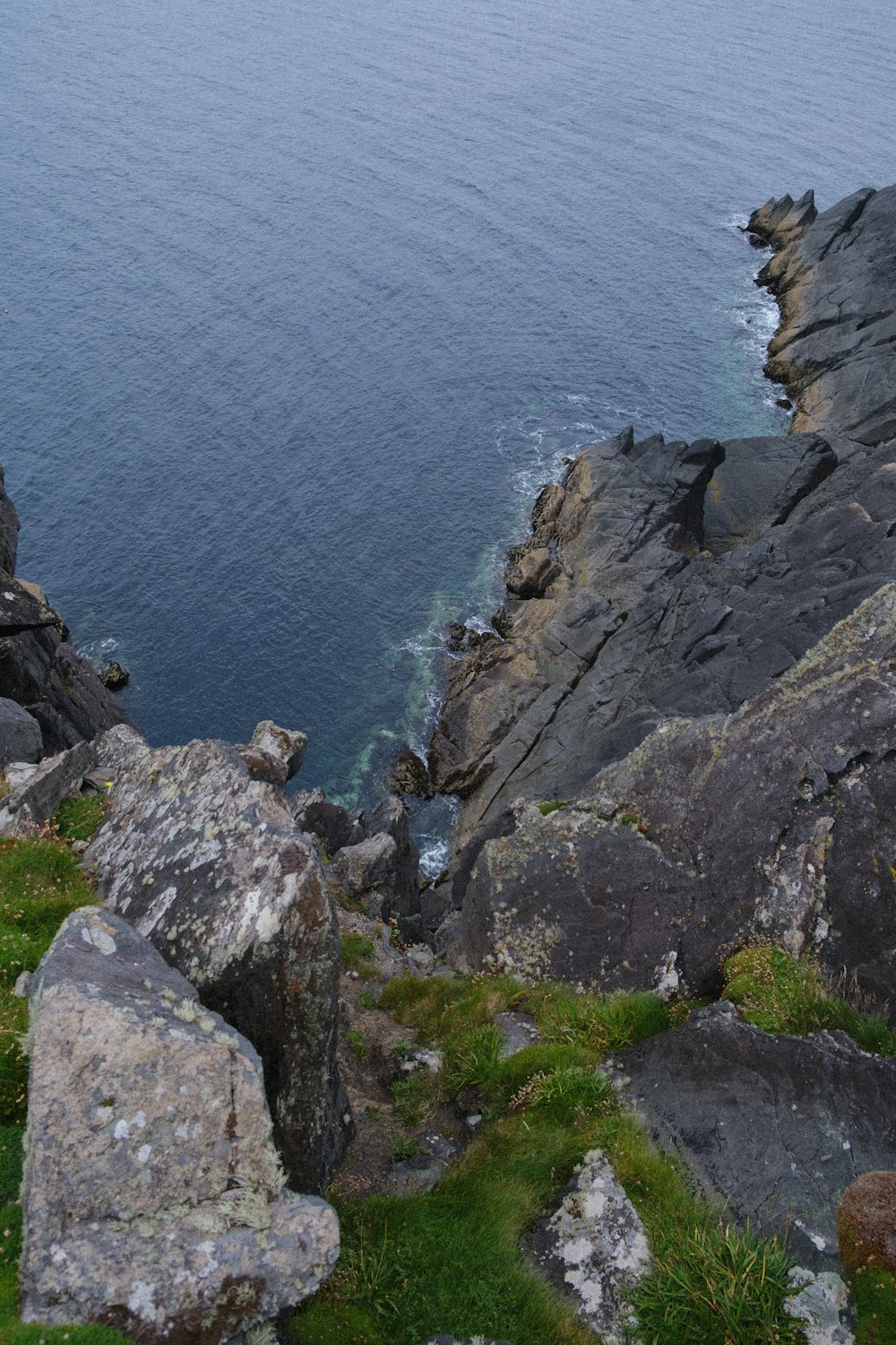 Montagna rocciosa grigia accanto al mare blu durante il giorno