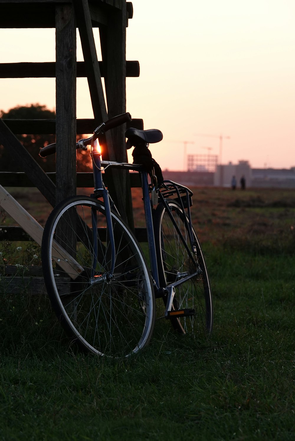 Bicicleta de cercanías negra cerca de la valla de madera marrón durante la puesta del sol