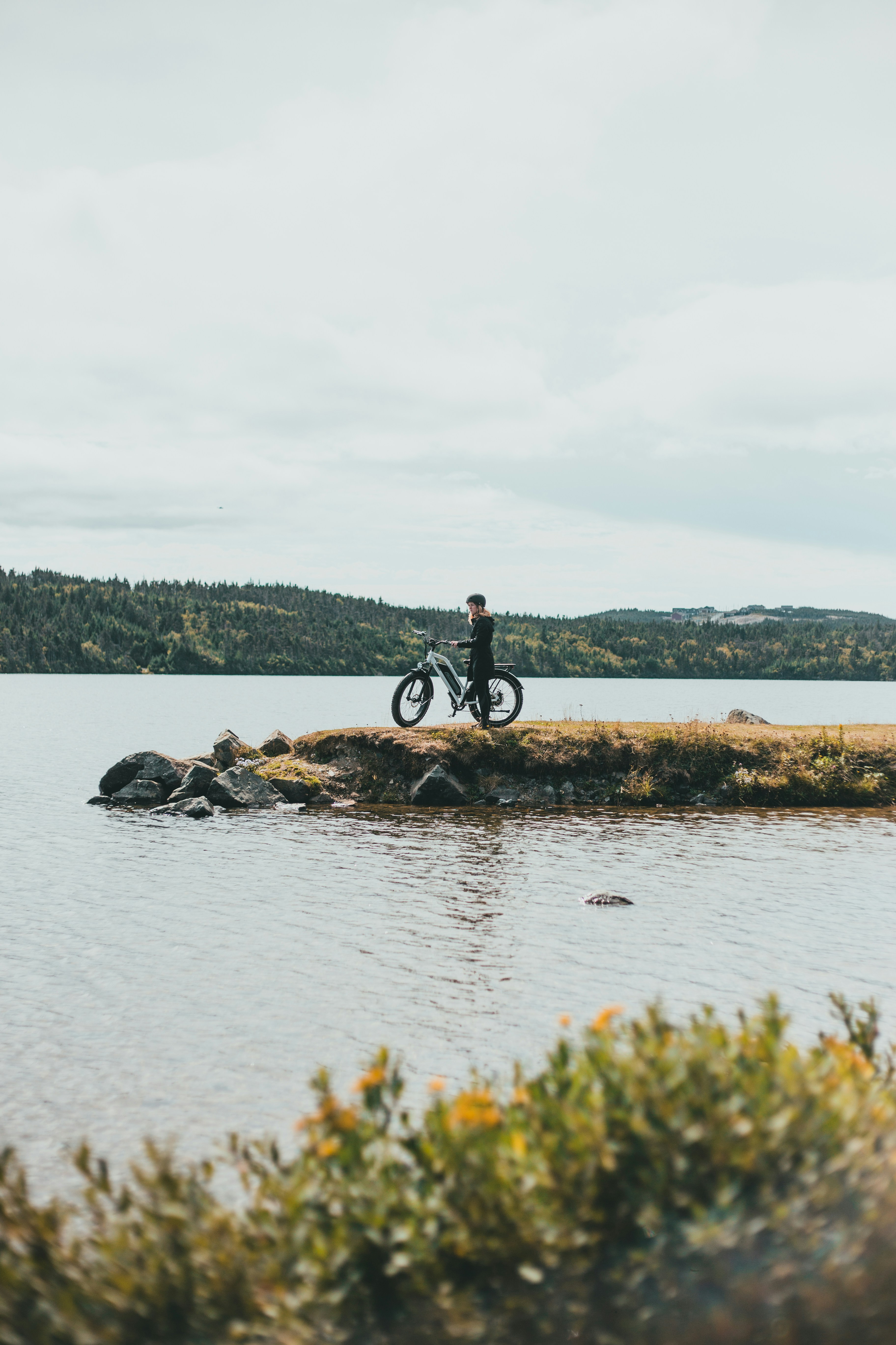 man in black shirt and black pants standing on rock near body of water during daytime