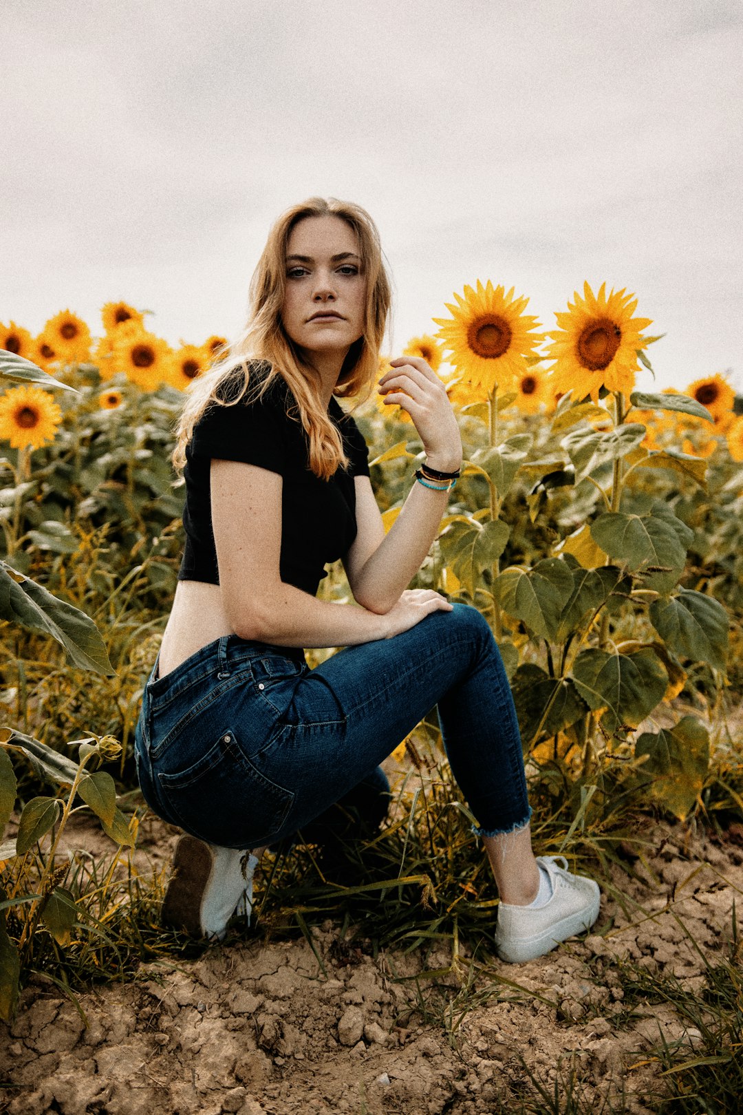 woman in black shirt and blue denim jeans sitting on brown grass field