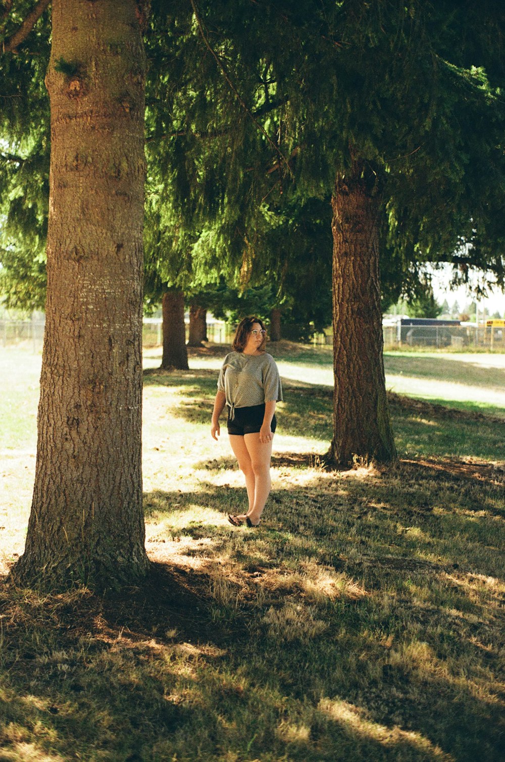 man in gray t-shirt and black shorts standing beside brown tree during daytime