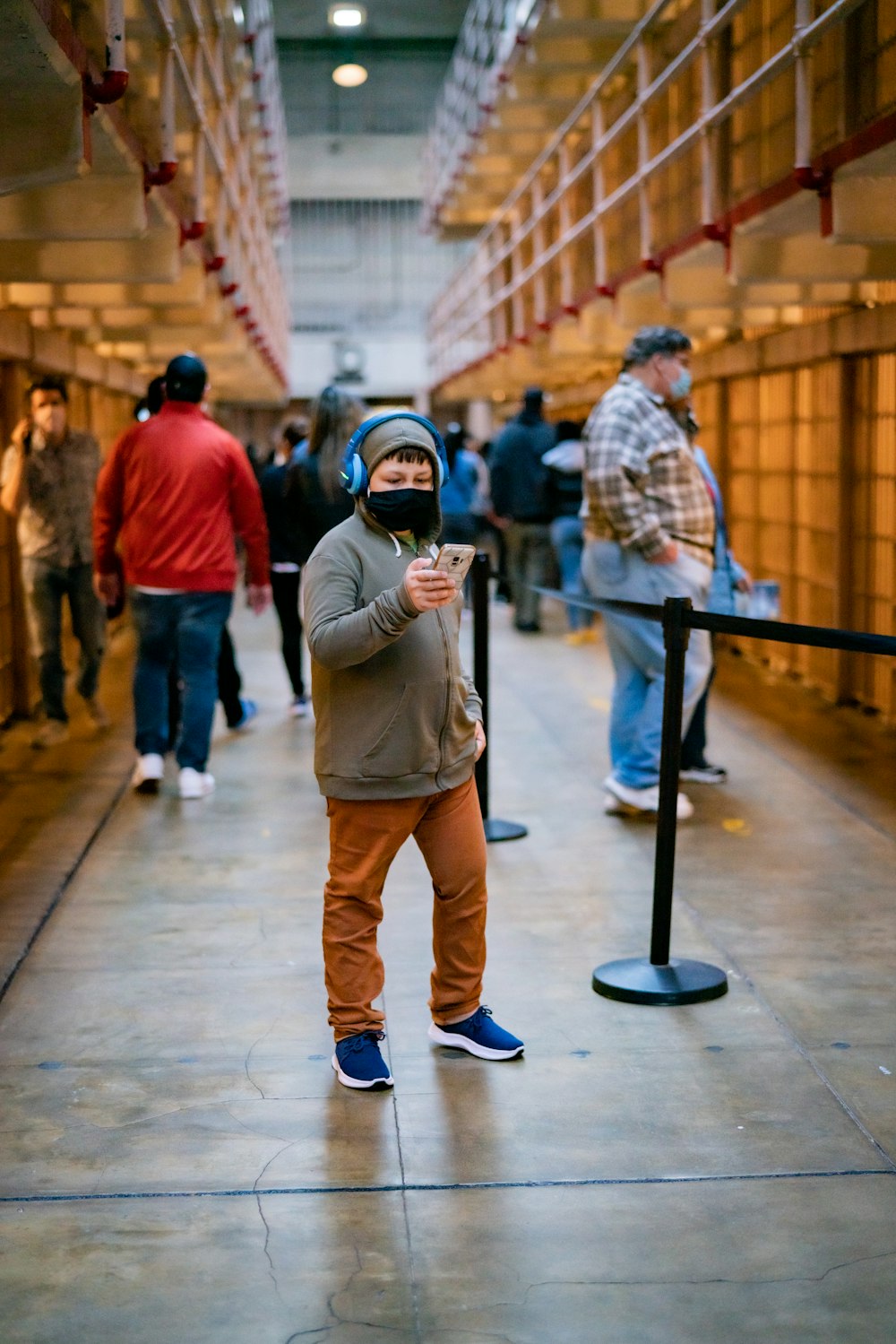 man in brown jacket and brown pants holding black smartphone