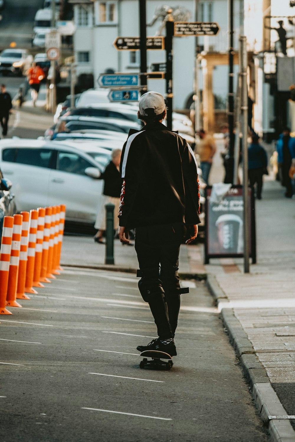 uomo in giacca nera che cammina sul marciapiede durante il giorno