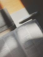 An open book with a pen resting on its pages.