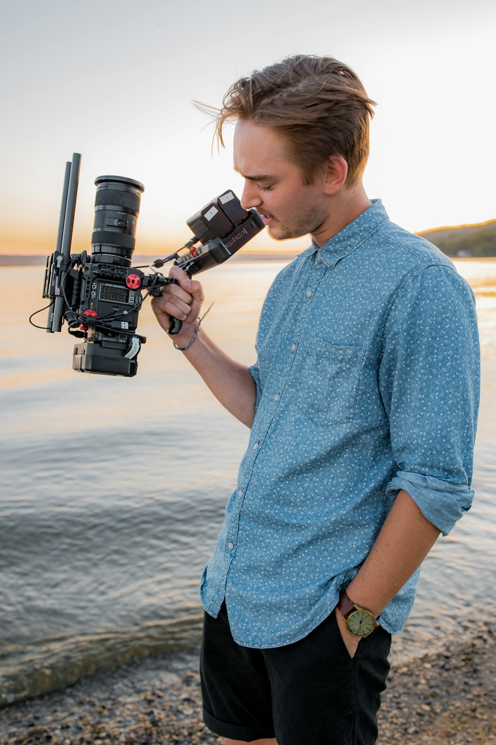 Mann im blauen Hemd mit schwarzer DSLR-Kamera