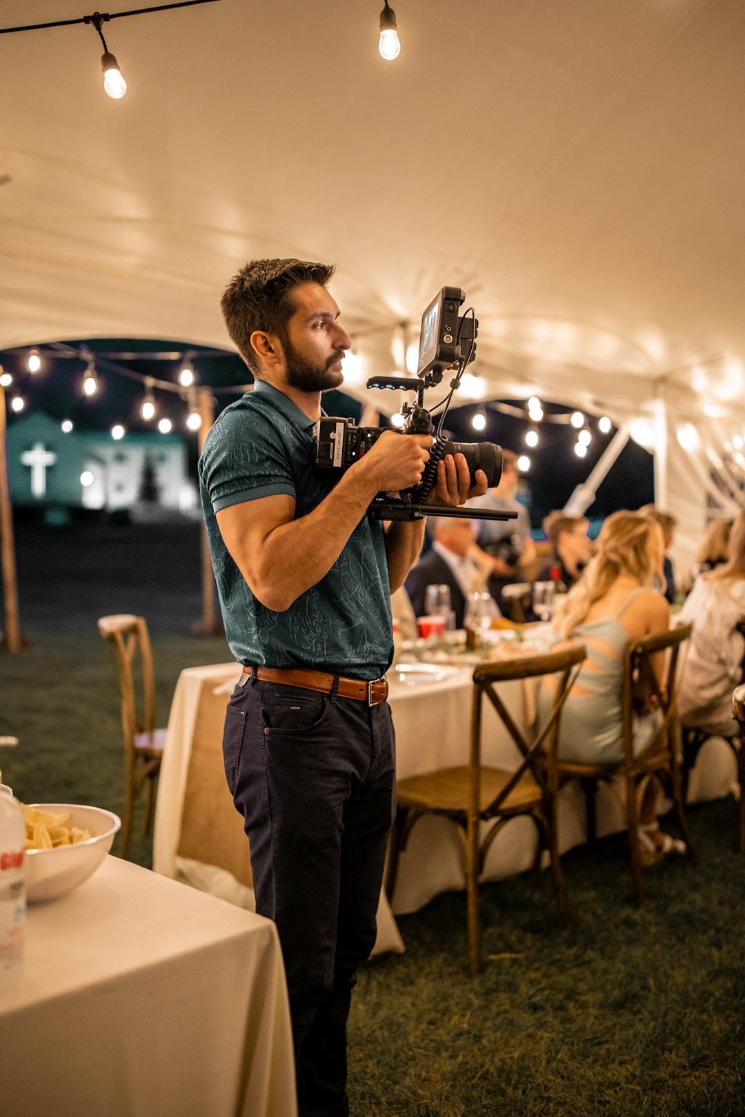 man in blue t-shirt and blue denim jeans holding black and gray camera