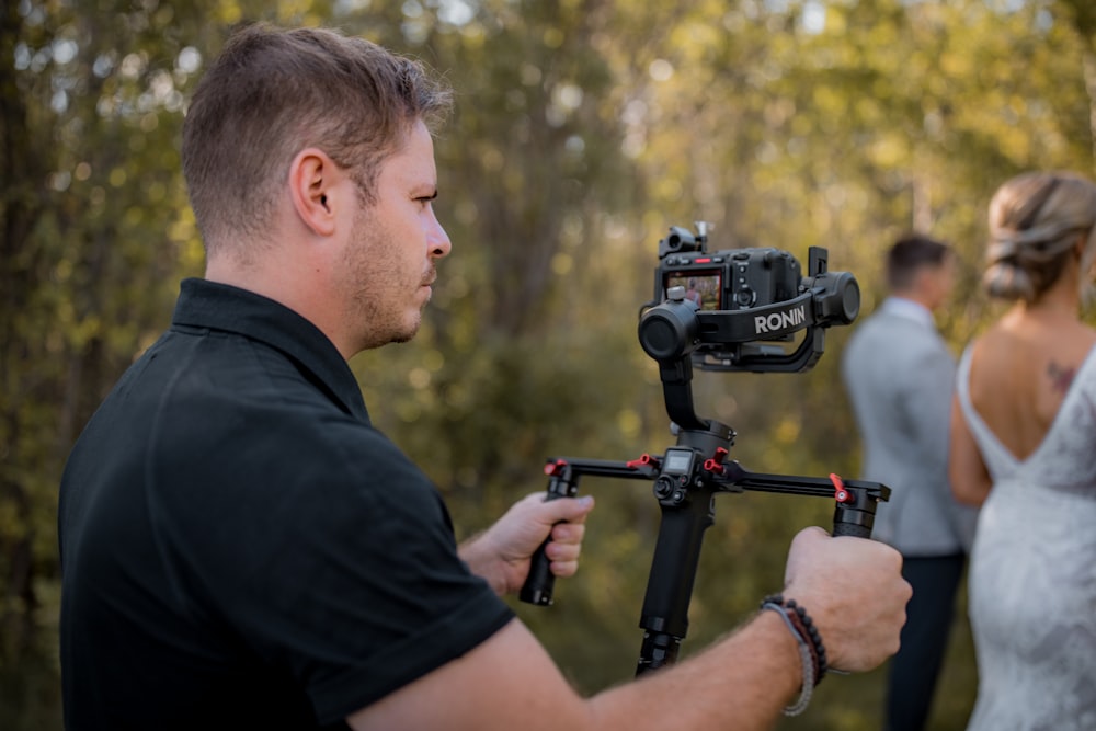 man in black t-shirt holding black video camera