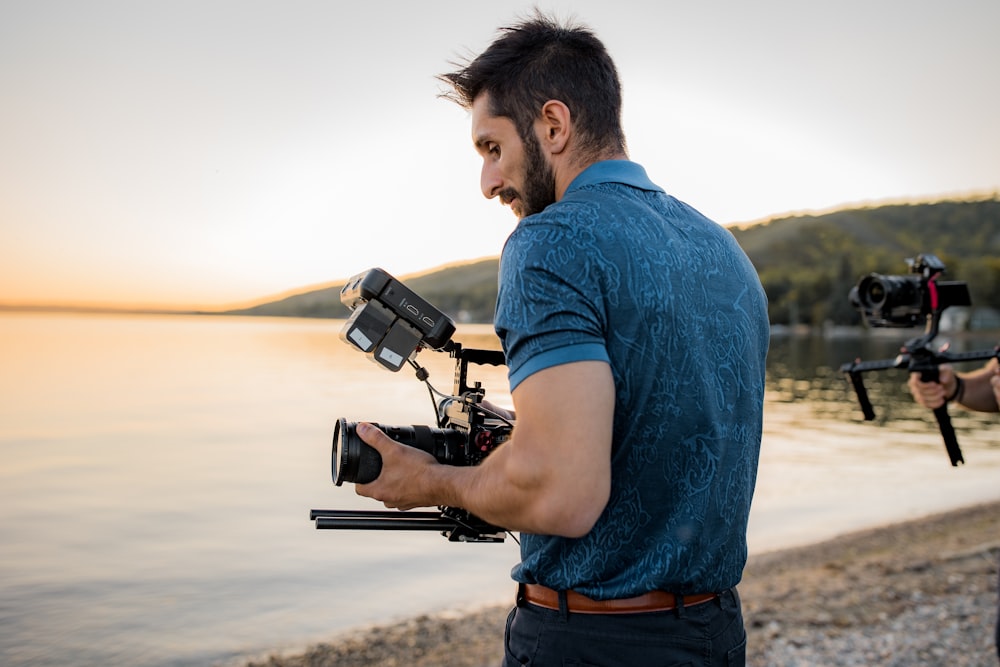 man in blue t-shirt holding black video camera