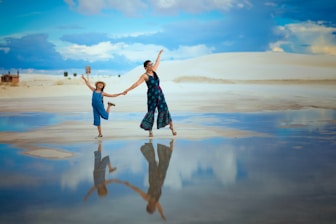 woman in blue and white dress standing on brown sand during daytime