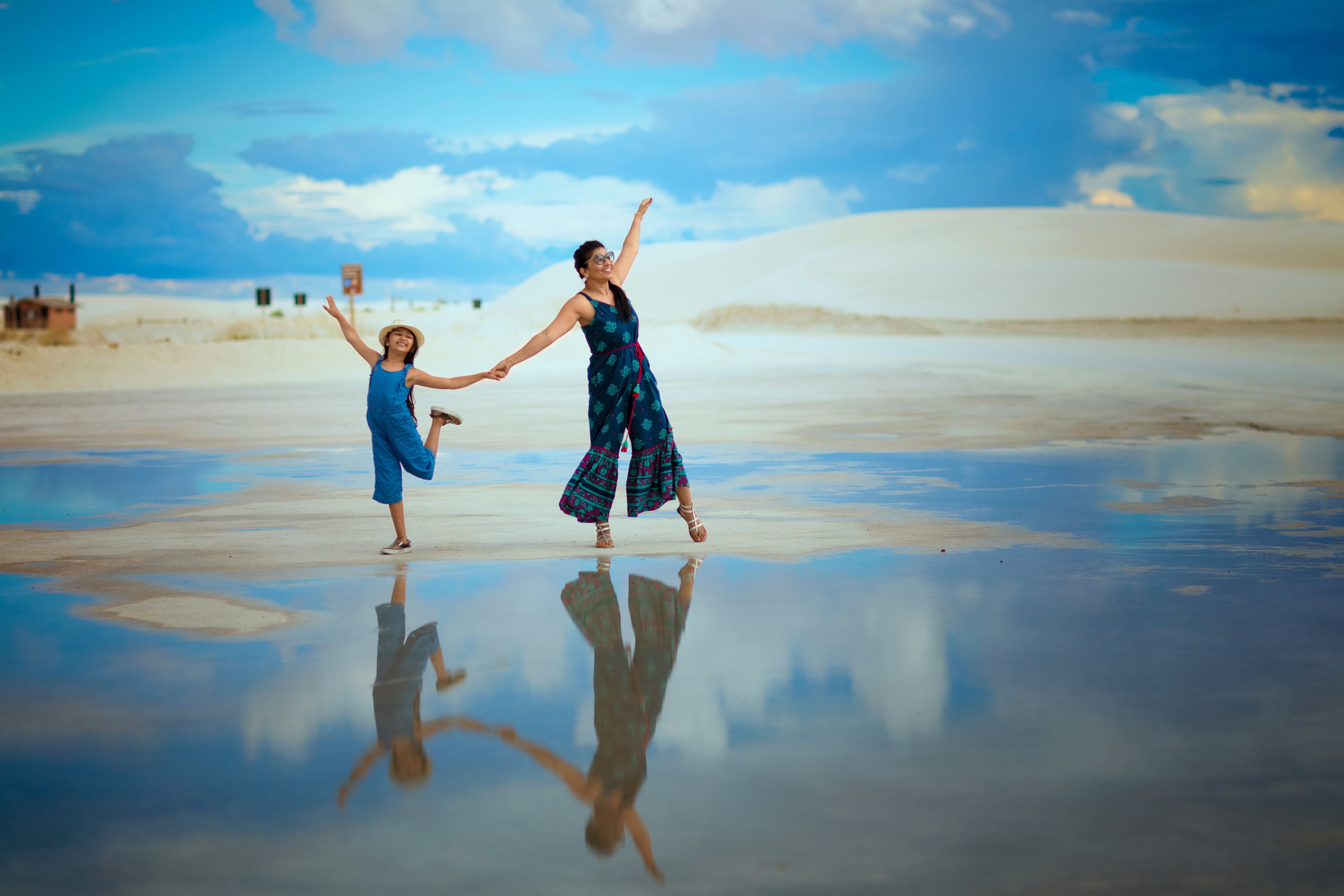 great photo recipe,how to photograph a family trip to white sands national park in new mexcio, united states. i found this puddle just after the rain and got these beautiful reflections; woman in blue and white dress standing on brown sand during daytime