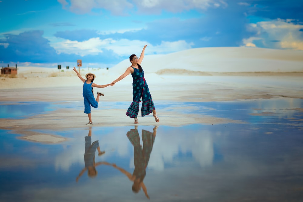 woman in blue and white dress standing on brown sand during daytime