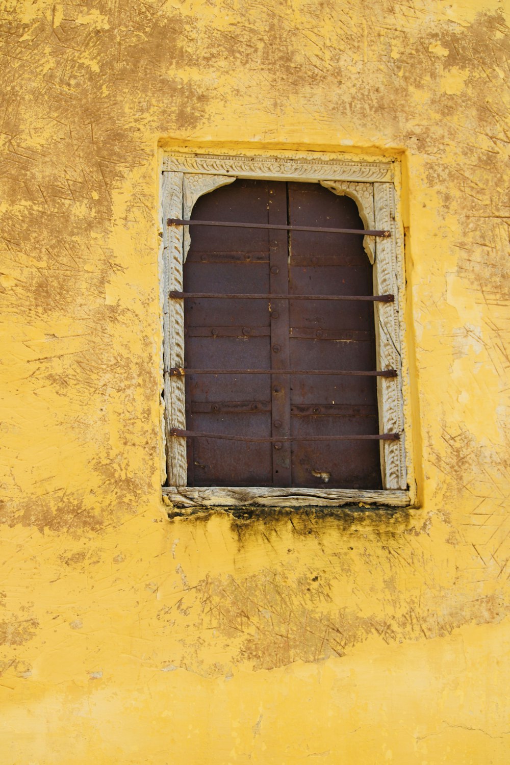 blue wooden window frame on yellow concrete wall