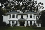 white and gray house near green grass field during daytime