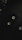 A vintage video cassette is placed on a dark surface, alongside part of a laptop keyboard in the top left corner and a watch in the bottom right. The lighting is dim and creates a moody atmosphere.