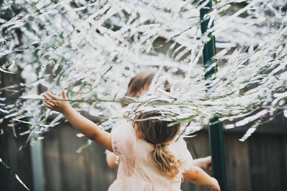 menina no vestido branco que está na grama verde durante o dia