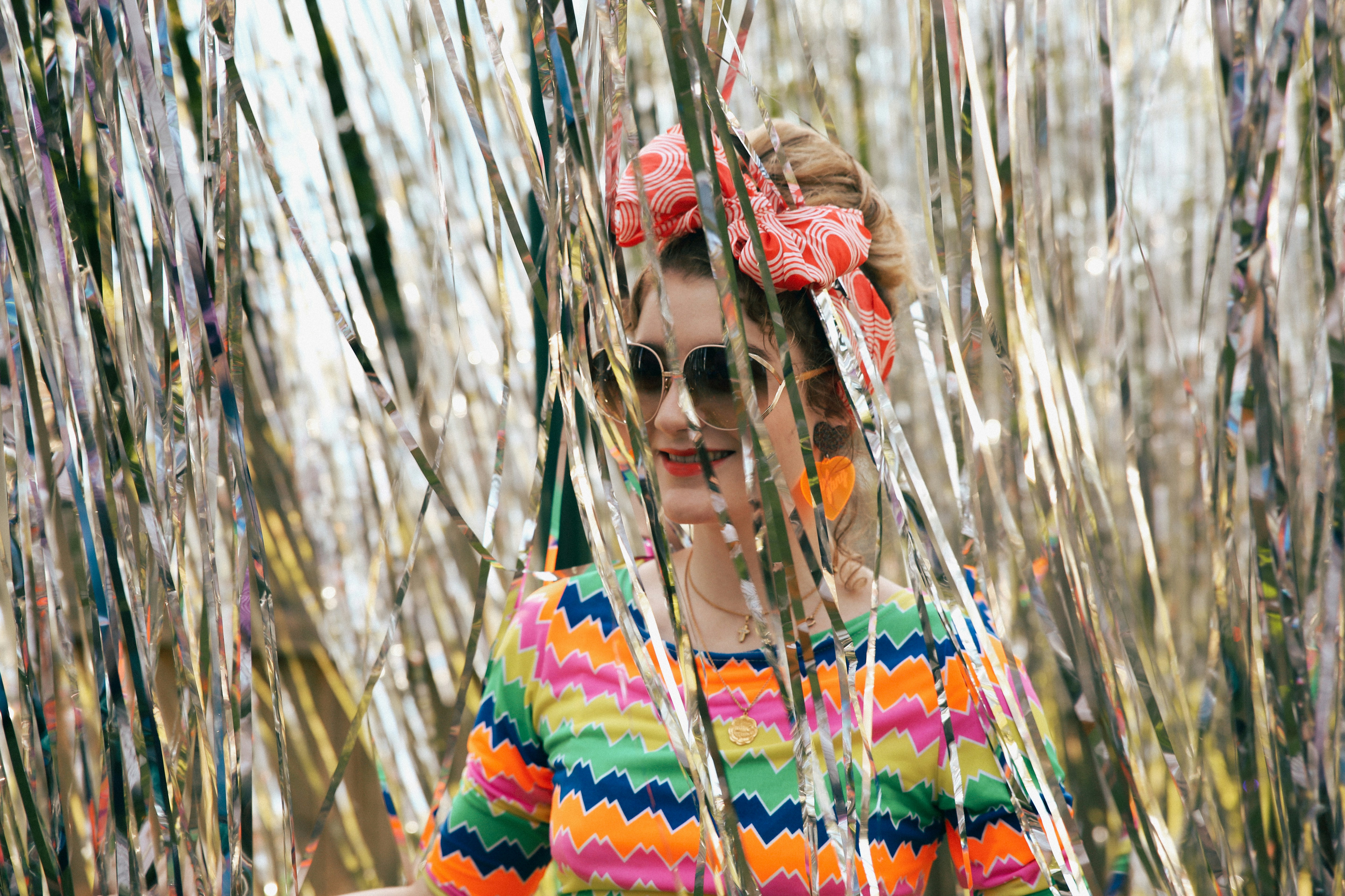 Woman wearing a colorful floral print dress standing in a sunlit field