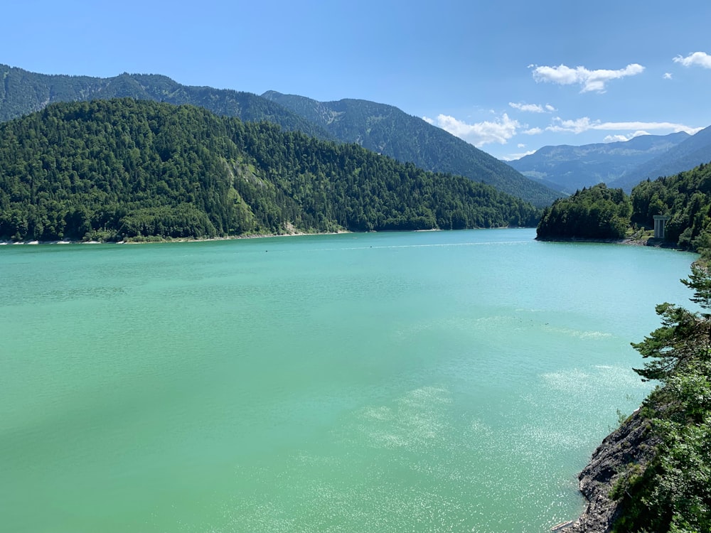 green lake surrounded by green mountains during daytime