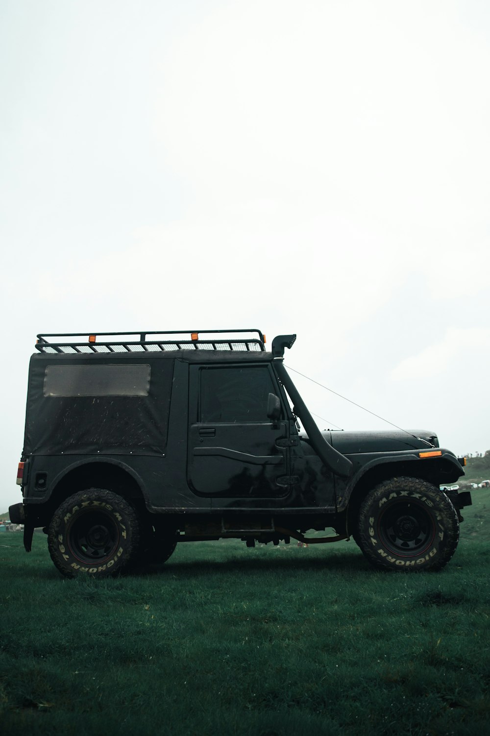 black and gray jeep wrangler on green grass field under white sky during daytime