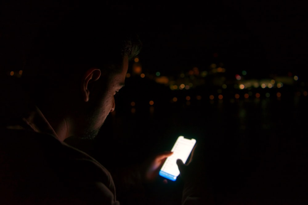 man in black shirt holding white smartphone