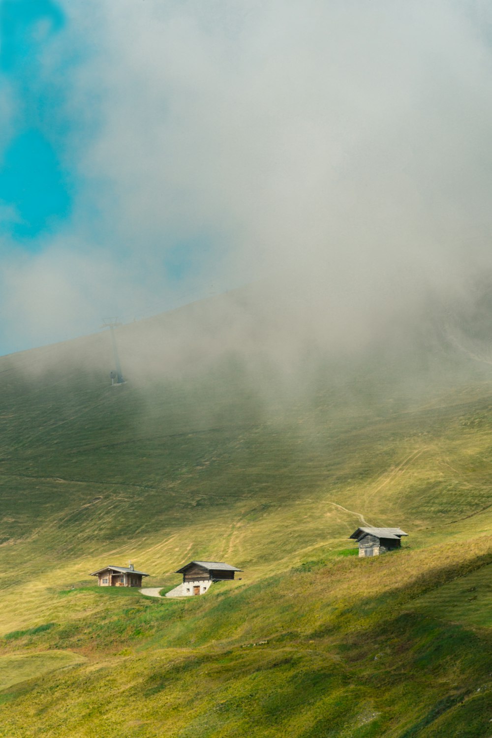 white and black house on green grass field near mountain under blue sky during daytime