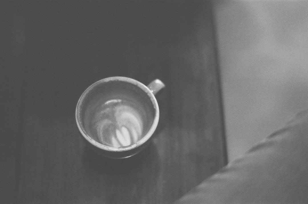 grayscale photo of ceramic mug on wooden table