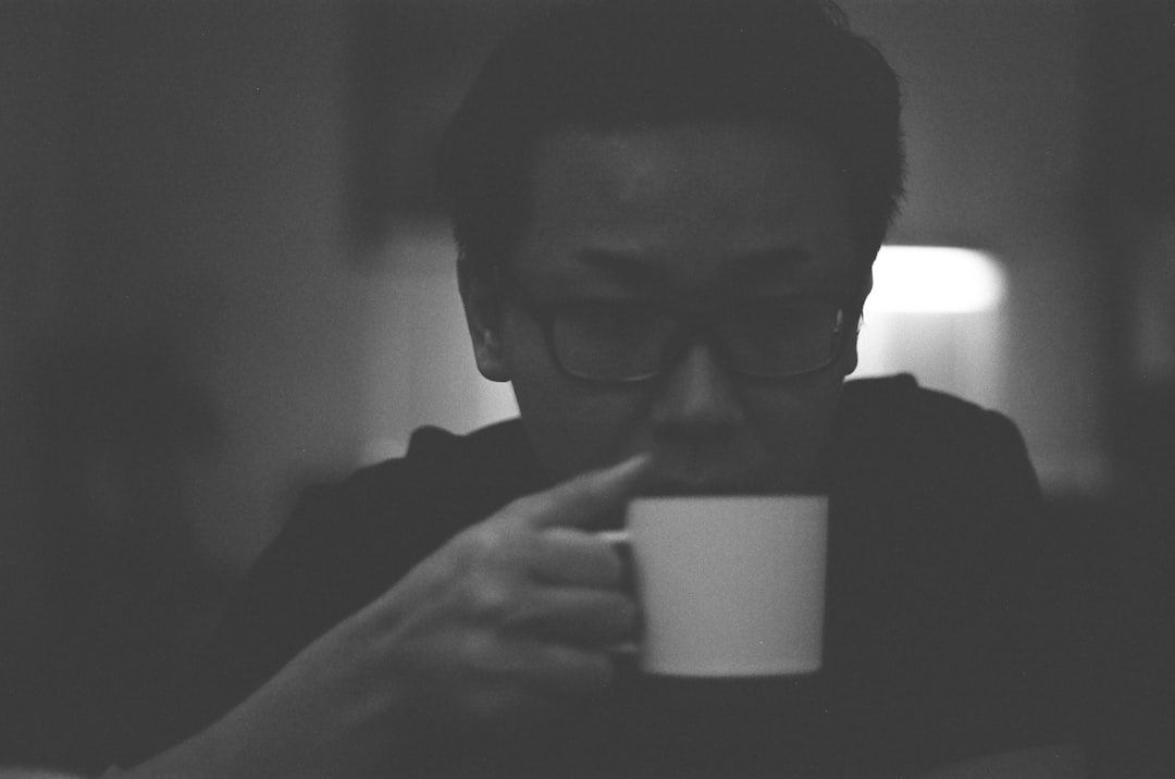 man in black shirt holding white ceramic mug