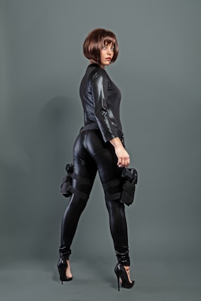 A confident woman in tactical gear standing in a shadowy urban alley, ready for action.