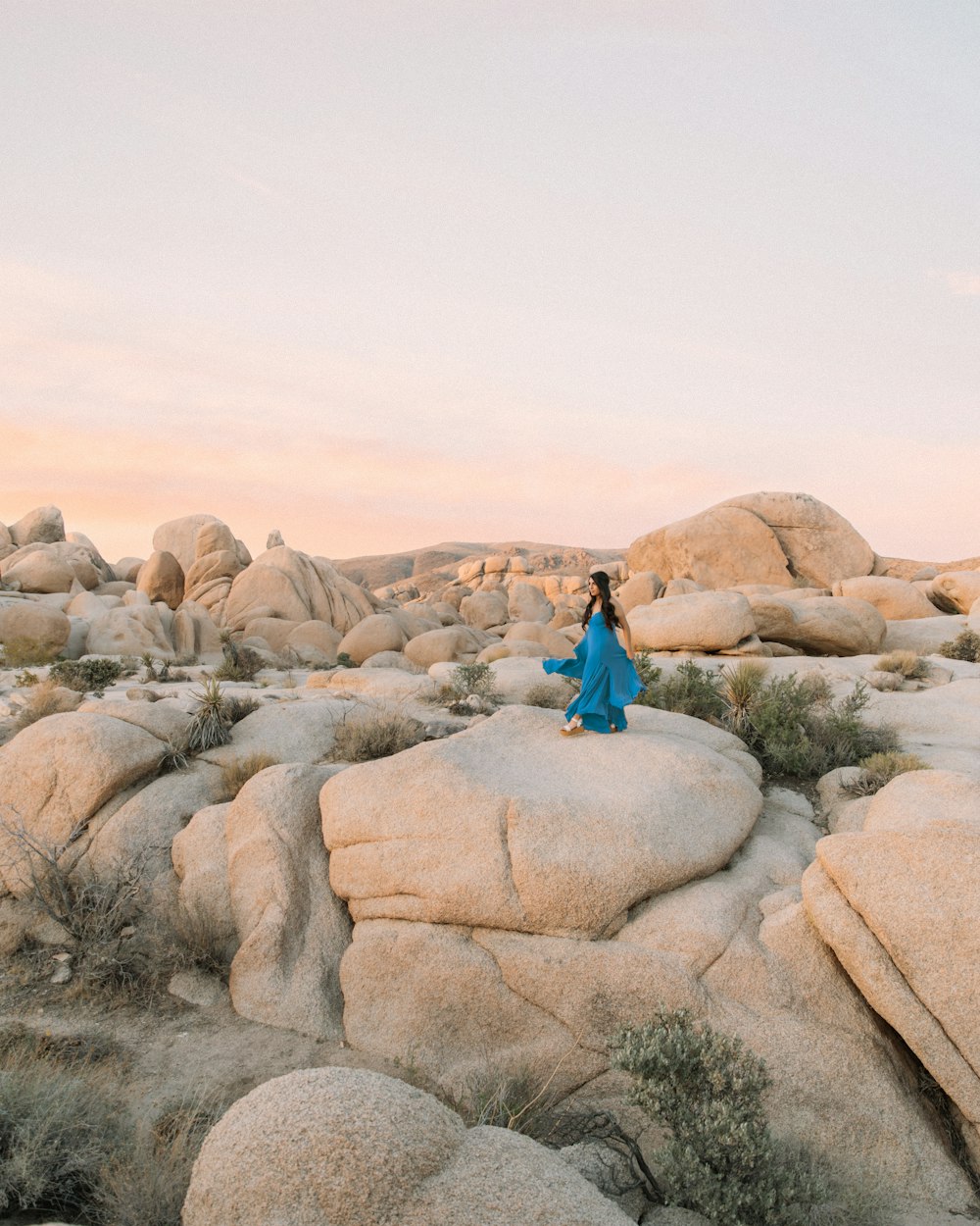 woman in blue dress sitting on rock formation during daytime