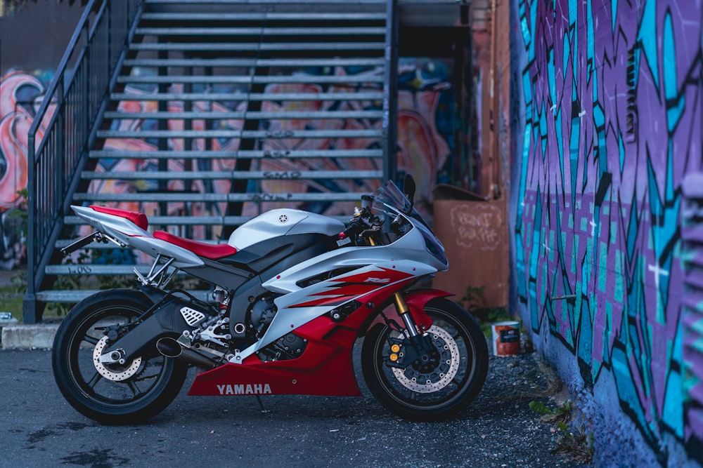 red and white sports bike parked beside wall
